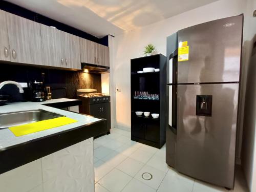 uma cozinha com uma geladeira de aço inoxidável e uma pia em Casa Familiar 4 Habitaciones con Agua Caliente, WiFi y Patio - Acepta Mascotas em Pereira