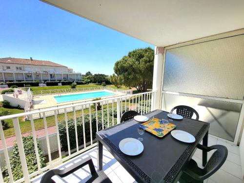 - une table sur un balcon avec vue sur la piscine dans l'établissement T2 Piscine, Terrasse Sud, Proche Plage - FR-1-92-740, à La Pironnière