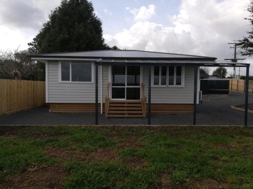 a small white shed with a pitched roof at Cottage in Hamilton