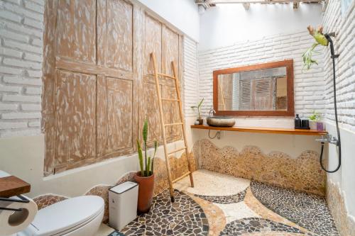 a bathroom with a toilet and a wooden door at Villa Sare - House with panorama rice field view in Yogyakarta