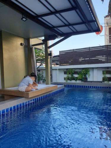 a man laying on a bench next to a swimming pool at สุวรรณภูมิอพาร์ทเม้นท์ in Suvarnabhumi Airport