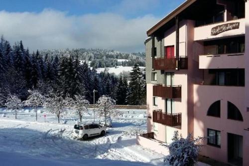 une voiture garée dans la neige à côté d'un bâtiment dans l'établissement Appartement avec balcon vue montagne à Bellevaux, à Bellevaux