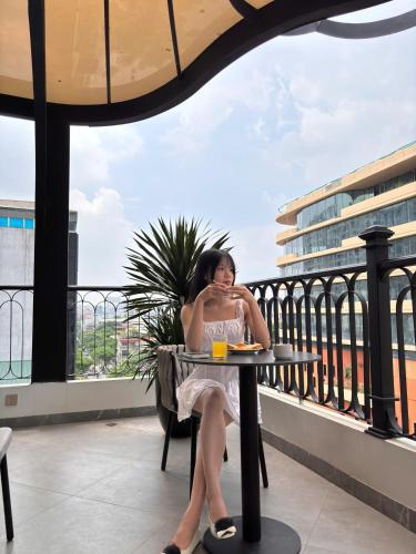 a woman sitting at a table on a balcony at 22 Land Hotel in Hanoi