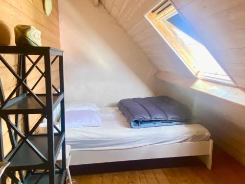 a small bed in a attic with a window at Chaleureuse Maison à Groix, 5 pers, 3 chambres - FR-1-813-31 in Groix