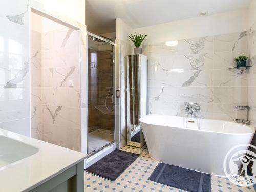une salle de bain blanche avec une baignoire et une douche dans l'établissement Chambres d'hôtes spacieuses près de la Loire - FR-1-622-116, à La Menitré