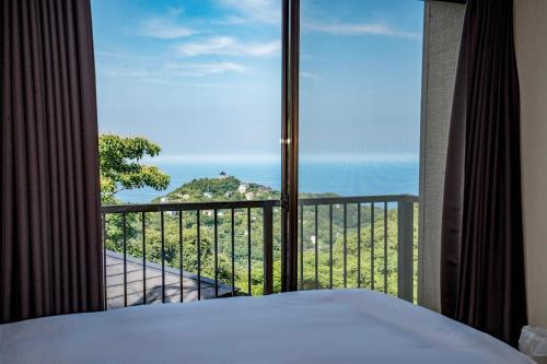 a bedroom with a large window with a view of the ocean at 熱海 海炉 天然温泉 花火見える 海を望む絶景ヴィラ in Atami