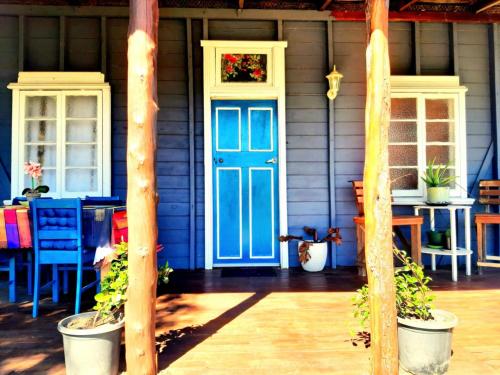 a blue door on a house with a table and chairs at Rosewood Cottage -Entire 2 bedroom home with Netflix & WiFi in Tambo