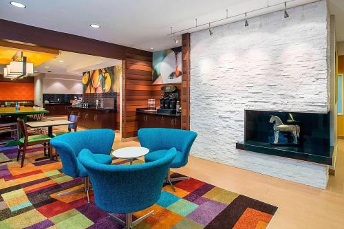 a living room with a fireplace and blue chairs at Wingate by Wyndham Oshkosh in Oshkosh