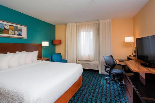 a hotel room with a bed and a desk and a television at Wingate by Wyndham Oshkosh in Oshkosh