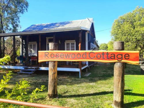 a wooden sign in front of a house at Rosewood Cottage -Entire 2 bedroom home with Netflix & WiFi in Tambo