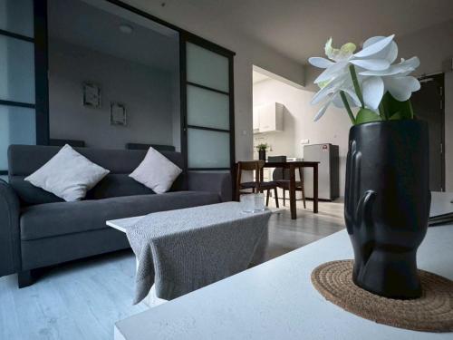 a living room with a blue couch and a vase with white flowers at 适合全家入住 Jesselton Quay高楼层日落景公寓 近Suria & Gaya街 Perfect for Families High-Floor Sunset Condo at Jesselton Quay Near Suria and Gaya Street in Kota Kinabalu