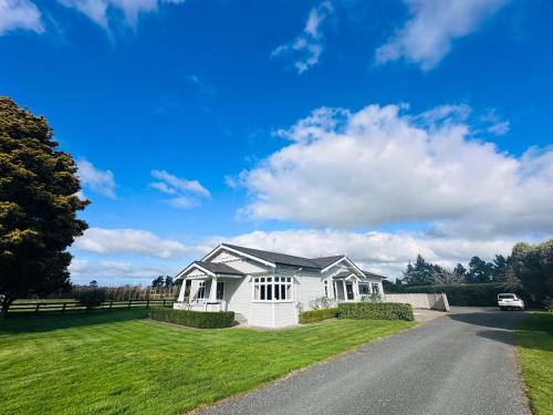 a white house on the side of a road at Villa Newstead Luxury Stay Near Hamilton in Newstead