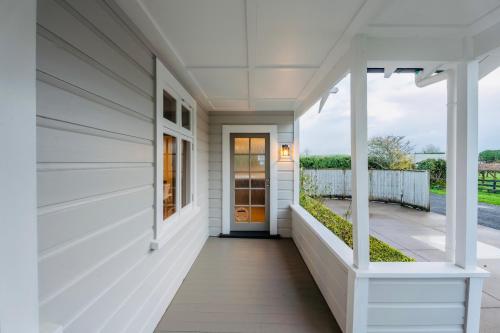 a front porch of a house with whiteiding at Villa Newstead Luxury Stay Near Hamilton in Newstead