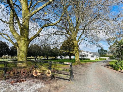 a fence in a field with trees and a house at Villa Newstead Luxury Stay Near Hamilton in Newstead
