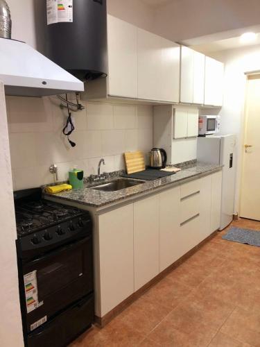 a kitchen with white cabinets and a sink and a stove at Apart Milo II in San Fernando del Valle de Catamarca