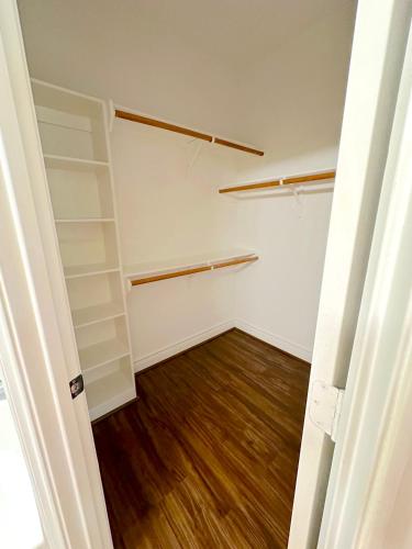 an empty closet with white shelves and a wooden floor at Spacious 5bed Houston Retreat Home in Houston