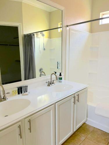 a bathroom with a sink and a mirror and a tub at Spacious 5bed Houston Retreat Home in Houston