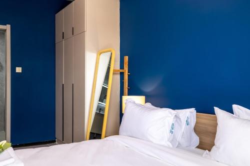 a bedroom with a blue wall and a bed with white pillows at Nandwa Ivy By YourHost, Kileleshwa, Nairobi in Nairobi