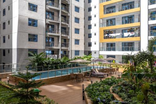 an apartment building with a pool and tables and chairs at Nandwa Ivy By YourHost, Kileleshwa, Nairobi in Nairobi