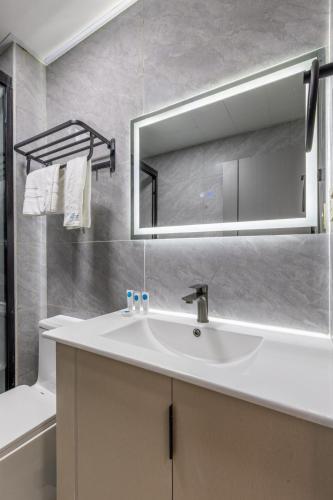 a bathroom with a white sink and a mirror at Nandwa Ivy By YourHost, Kileleshwa, Nairobi in Nairobi