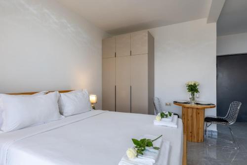 a bedroom with a white bed and a table and chairs at Nandwa Ivy By YourHost, Kileleshwa, Nairobi in Nairobi