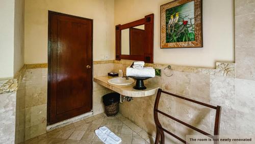 a bathroom with a sink and a wooden door at Svarga Bebek Villas in Ubud