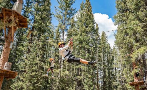a man on a zip line in the forest at Spacious Designer 3BR Victorian with AC & Hot Tub in Aspen