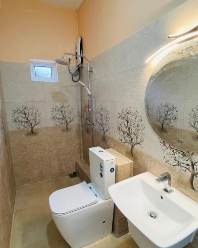 a bathroom with a sink and a toilet and a mirror at Kandy Villa Grey in Talatuoya