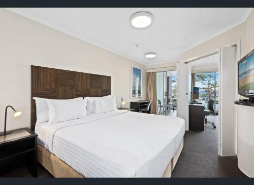a bedroom with a large white bed and a desk at Grande Esplanade Manly Central in Sydney