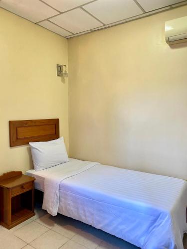 a bedroom with a white bed and a table at Don Bosco Hotel School in Sihanoukville