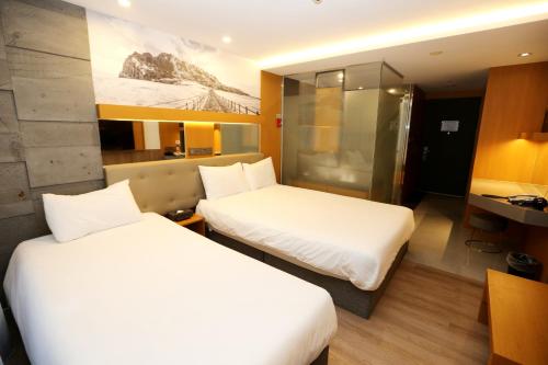 a hotel room with two beds and a desk at Asia Jeju in Jeju