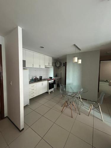 a kitchen with white cabinets and a table and chairs at APARTAMENT BEACH FORTALEZA in Fortaleza