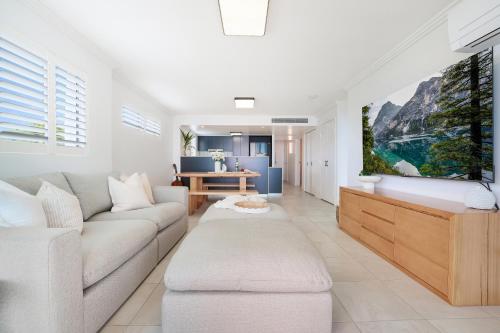a living room with a couch and a tv at Dwell 23, Oceanfront Apartment in Bargara