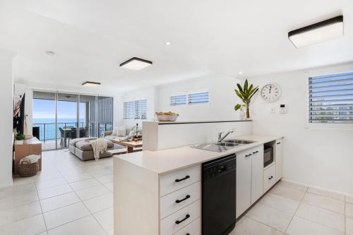 a kitchen and living room with a view of the ocean at Dwell 23, Oceanfront Apartment in Bargara