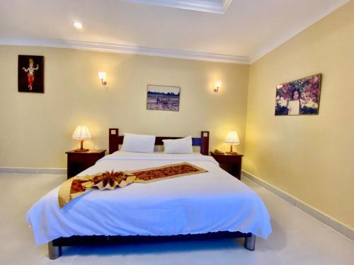 a bedroom with a large white bed and two lamps at Don Bosco Hotel School in Sihanoukville
