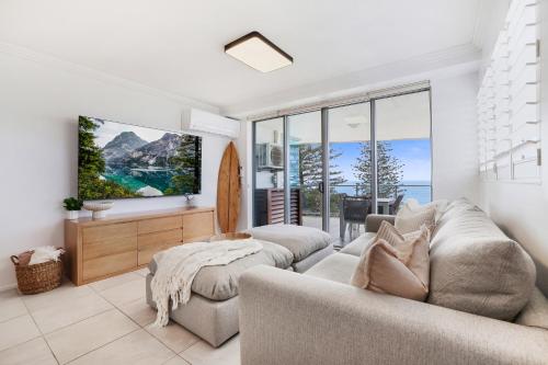 a living room with two couches and a tv at Dwell 23, Oceanfront Apartment in Bargara