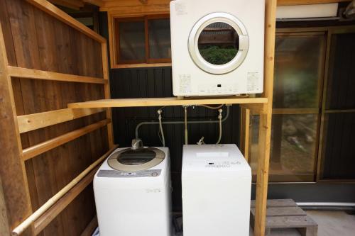 a washing machine and a washer and dryer under a shelf at 農ある暮らしの宿古民家天地 in Minamiizu