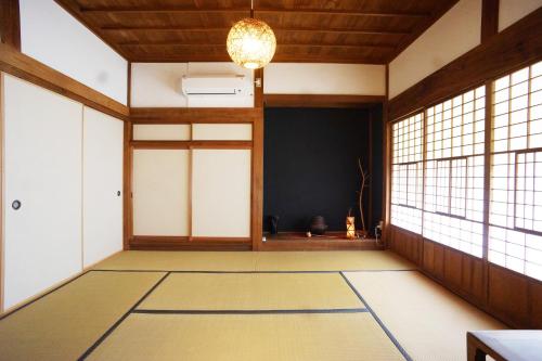 an empty room with windows and a chandelier at 農ある暮らしの宿古民家天地 in Minamiizu