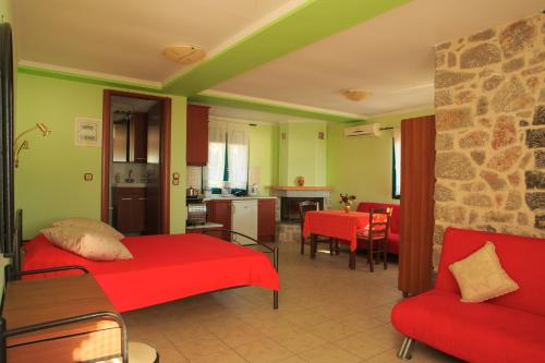 a living room with a red bed and a kitchen at To Asteri in Avgonyma