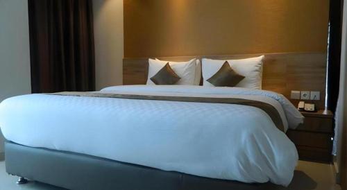 a large white bed in a hotel room at Wing Hotel Kualanamu Airport in Medan