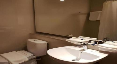 a bathroom with a toilet and a sink and a mirror at Wing Hotel Kualanamu Airport in Medan