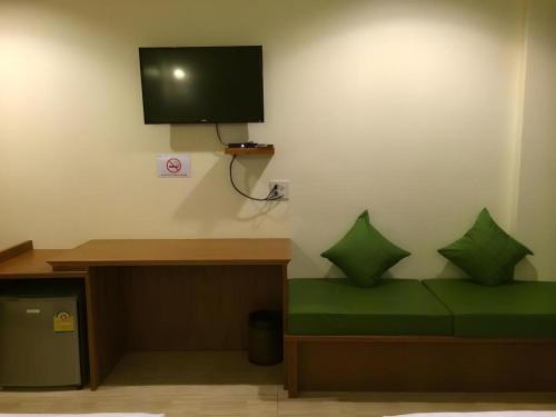 a room with a bed with green pillows and a tv at The Green Hotel in Ko Lipe