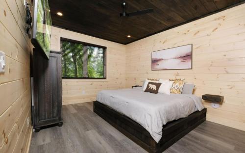 Un dormitorio con una cama en una habitación con paredes de madera. en Tennessee Swim, en Pittman Center