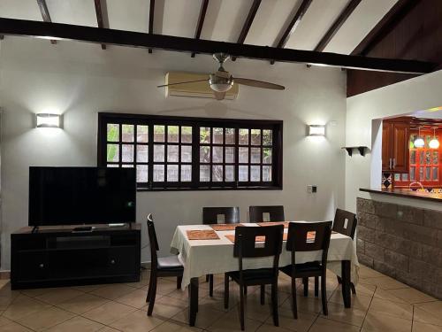 a dining room with a table and chairs and a television at Casa Tranquilo in Chinandega