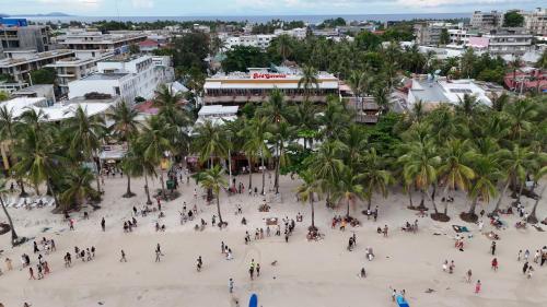 a group of people walking on a beach with palm trees at Red Coconut Beach Hotel Boracay in Boracay
