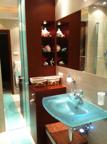 a bathroom with a blue sink and a shower at Patio Mare Amber in Sopot