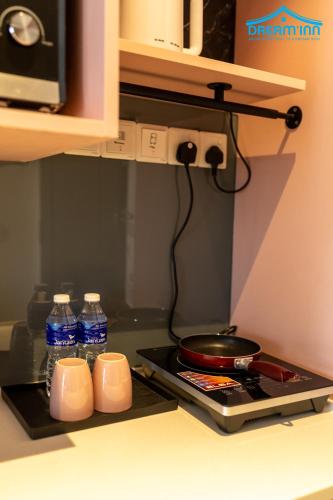 a stove top with two cups and bottles of water at Paxtonz Empire City Damansara Petaling Jaya by Dream Inn in Petaling Jaya