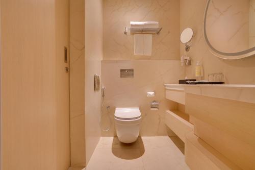 a white bathroom with a toilet and a sink at Lemon Tree Hotel, Erode in Erode