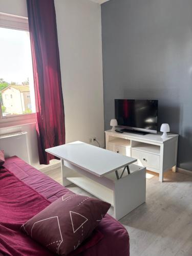 ein Zimmer mit einem Bett, einem Fernseher und einem Tisch in der Unterkunft Studio tout équipé pour 2 a 15 minutes de valras plage in Béziers