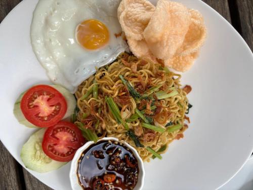 a plate of food with noodles and an egg and tomatoes at The Lookout Cabin in Pupuan Tabanan Bali in Tabanan